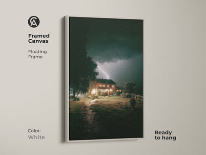 White framed canvas featuring a lightning storm over a house. The detailed artwork adds a modern touch. This framed canvas is ready to hang and will enhance any room's decor.
