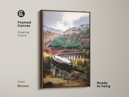 A framed canvas with a brown floating frame displays scenic railway wall art. The vintage train print features a steam train crossing a viaduct. This viaduct landscape art features earthy browns and forest greens. Ready to hang traditional train artwork for train enthusiasts.
