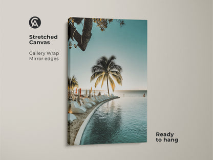 Stretched canvas coastal art print. The tropical beach wall art shows a palm tree ocean view and infinity pool. Enjoy relaxed summer vibes with this blue teal coastal decor. A perfect beach house wall hanging.