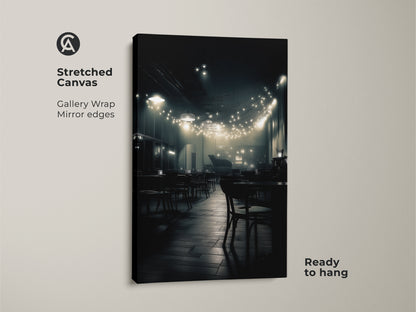 A stretched canvas showcases a monochrome cafe scene. Soft lighting from string lights illuminates empty tables and chairs. The gallery wrapped edges offer a modern seamless look. This ready-to-hang art enhances any room.