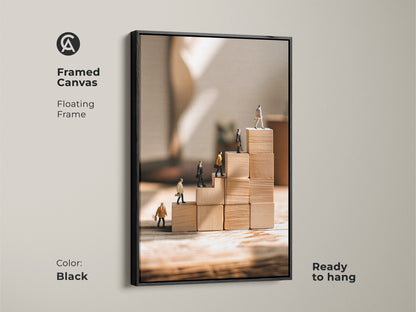 Framed canvas of miniature people climbing wooden blocks features a sleek black floating frame This motivational office artwork adds a conceptual touch to any workspace Ready to hang this beige tan minimalist canvas print is perfect for inspiring success and career growth An ideal entrepreneur gift for a contemporary desk decor