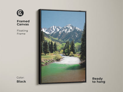 Framed canvas artwork of a mountain river landscape. The floating frame enhances the scenic nature art. It features snow-capped peaks and lush pine trees. This rustic decor is ready to hang in black.