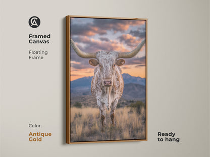 Framed canvas of a longhorn steer with an antique gold floating frame. This rustic western artwork showcases a mountain sunset. This farmhouse landscape art is ready to hang. It's a nice cowboy gift.