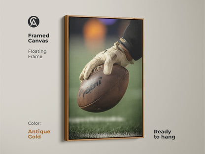 Framed canvas art shows a football player's hand gripping the ball. The floating antique gold frame enhances the sports action photography. Ready to hang this print is perfect for a game room. A great gift for any NFL fan who loves gridiron sports themed decor.