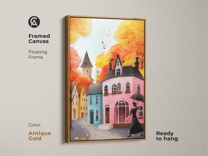 Framed canvas art print of a watercolor autumn cityscape with an antique gold floating frame. The artwork features a woman with an umbrella and charming houses. Ready to hang and perfect for fall decor. The warm colors and eclectic style add a cozy touch to your home. This autumn street scene print is a great gift.