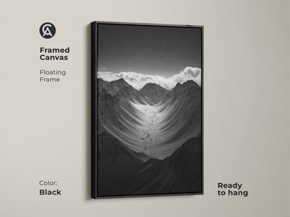 Framed black and white mountain art print with a floating frame. This monochrome canvas art is ready to hang. The hikers are ascending a vast snowy mountain range. This nature scenery wall art adds adventure to any space.