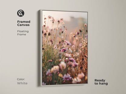 Framed canvas with a white floating frame showcasing wildflower artwork. Ready to hang this botanical bedroom decor features soft pinks and peach tones. The impressionistic canvas adds a touch of nature and elegance to any space.