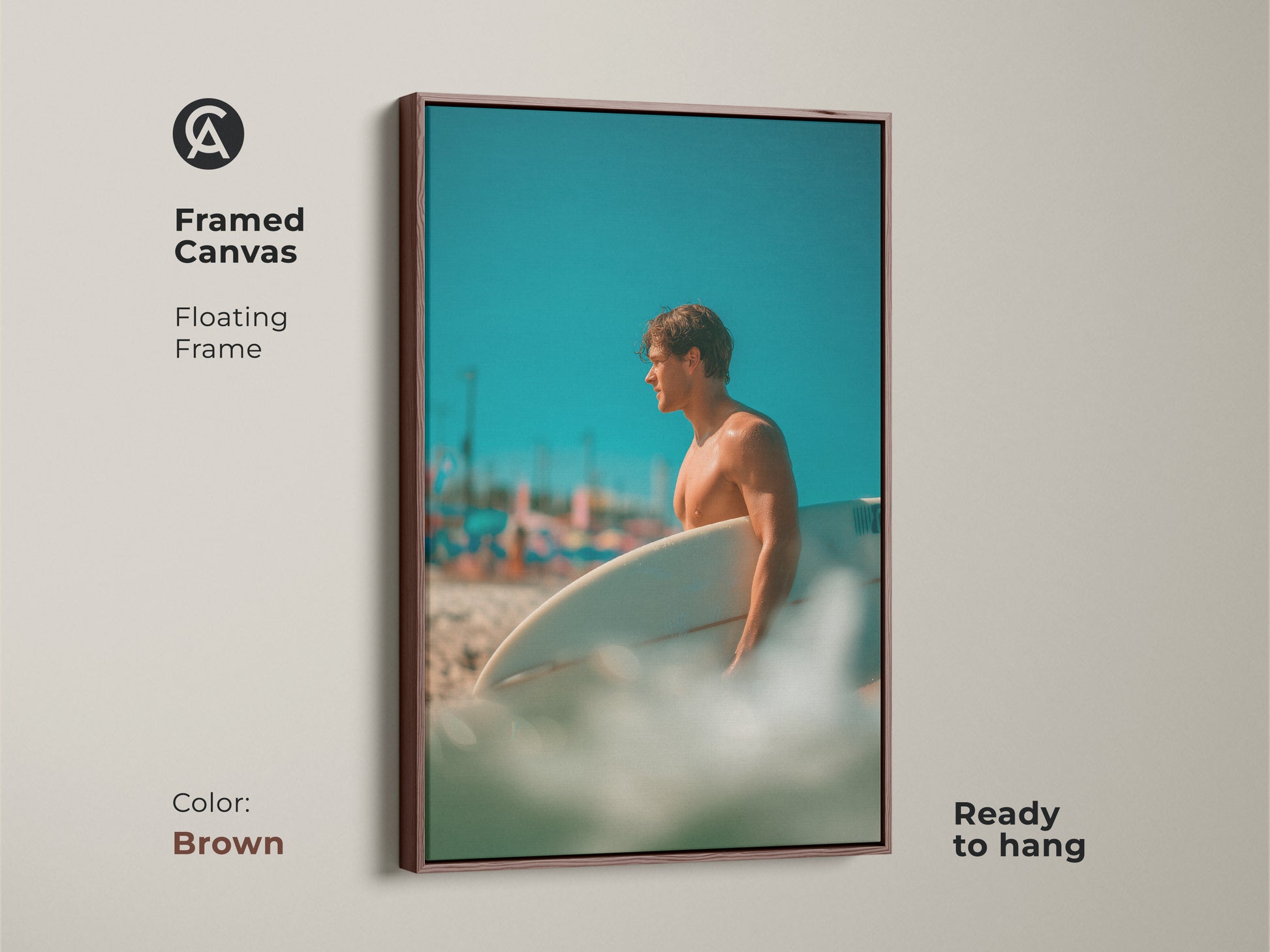 Framed canvas art featuring a surfer. The floating frame has a brown color. The image showcases a man holding a surfboard on a beach with a blue sky. This framed art is ready to hang.
