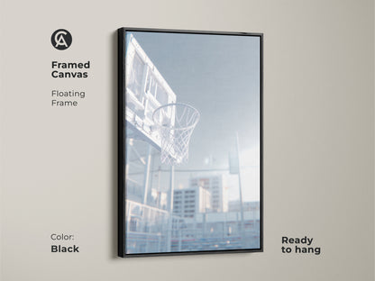 Black framed canvas art print of a basketball hoop. This floating frame is ready to hang. The low angle shot captures the net. Sunlight shines through the clear backboard. Decorate your home today.