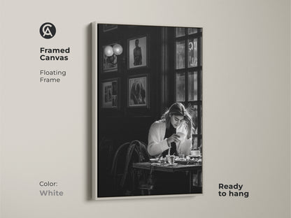 White framed canvas of a monochrome cafe scene. The contemporary black and white photojournalism style artwork features a woman with coffee. Ready to hang with a floating frame. Adds a minimalist touch to modern dining rooms cafes and home offices.