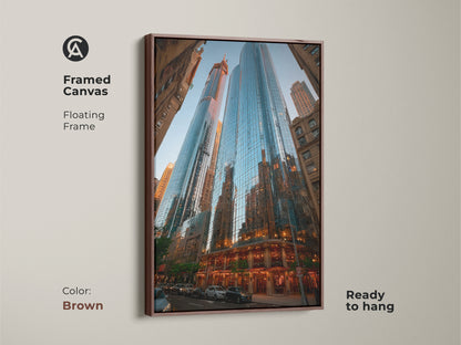 A framed canvas showcasing blue cityscape artwork. The modern skyscraper canvas has a floating brown frame. This contemporary architecture decor is ready to hang. Ideal office building art for metropolitan art print lovers. Perfect for housewarming.