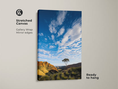Stretched canvas of an Australian Outback mountain art print. The lone tree landscape wall art captures the serene blue sky. This photorealistic Outback decor is ready to hang with gallery wrapped mirror edges. Its ideal for adding outdoor adventure to your living room or bedroom.