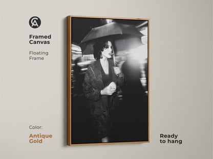 The antique gold floating frame enhances the elegance of this canvas. This framed canvas art arrives ready to hang. This striking street photography print features a monochrome woman with umbrella. A perfect fusion of fashion and art for chic spaces. Enhance your contemporary home.