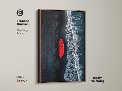 Framed canvas art featuring a red boat on a beach with black sand. The artwork has a rich brown floating frame. This canvas is ready to hang and will elevate any room's decor. A perfect addition to your art collection.