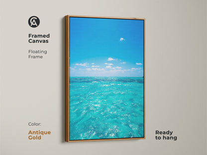 Framed canvas of a turquoise ocean view with a floating frame in antique gold. This coastal beach wall art is ready to hang. The blue sky water artwork is perfect for residential blue art prints. Add a calm ocean wall hanging to your living room.