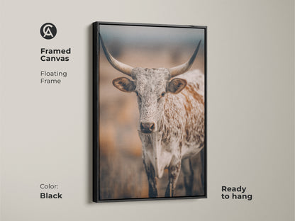 Framed canvas featuring Longhorn Cow artwork. The floating frame adds a modern touch to the rustic Texas wildlife. The canvas is black in color and ready to hang. It is ideal for farmhouse decor. This print enhances any living space with its country charm.