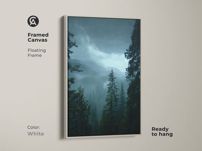 Framed canvas print of a misty forest landscape with a white frame. This pine tree artwork showcases deep green nature art. Ready to hang this print brings a tranquil mountain view to any space. Ideal for modern rustic decor.