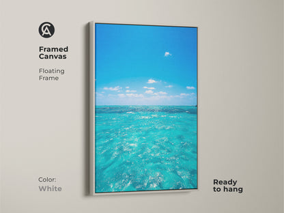 Framed canvas art of turquoise ocean waves with a white floating frame. Coastal beach house wall art featuring a realistic seascape. This blue water sky landscape painting enhances any room with seaside nature.