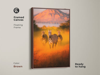 Framed canvas art of zebras in the African savanna with a floating brown frame. This wildlife artwork is ready to hang. Its warm earth tones are ideal for eclectic decor and a thoughtful housewarming gift. Enhance your bedroom or living room with this animal print. A safari theme with orange savanna colors.