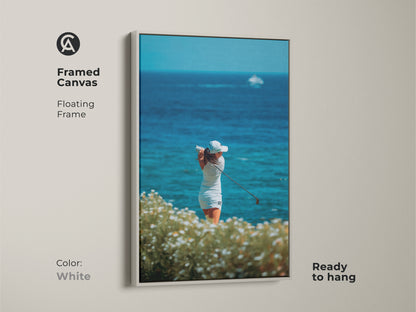 White framed canvas art showcasing a female golfer. This stylish artwork captures a woman golfer in action against a beautiful ocean backdrop. The white floating frame is ready to hang creating a clean modern look.