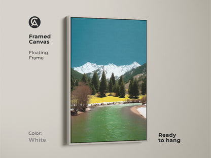 Framed canvas with a floating frame featuring a mountain river artwork. The white frame accents the pine trees snowy peaks and teal-green water. Ready to hang this artwork brings a fresh touch. A great gift for outdoorsy people.