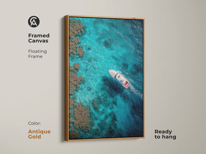 Antique gold framed canvas displays a boat sailing on turquoise waters. This floating frame art print is ready to hang. The aerial shot captures the beauty of the ocean and coral reefs.