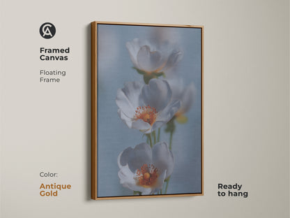 Framed canvas showcasing delicate white flower artwork. This soft focus botanical art is in an antique gold floating frame. Light blue floral canvas enhances any space. This nature inspired artwork is ready to hang. A perfect housewarming gift for lovers of gentle flower artwork.