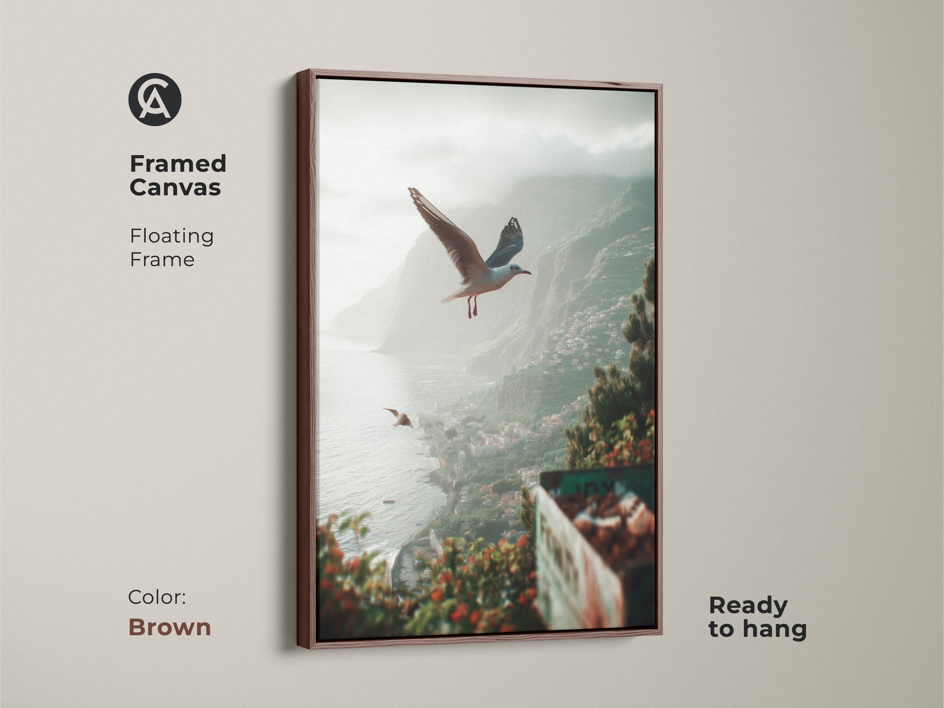 Framed canvas in brown showcasing teal green grey coastal artwork. It features seagulls gracefully flying over a quaint seaside town. The beach landscape art print is ready to hang. A calming serene ocean view is brought by this coastal home decor gift.