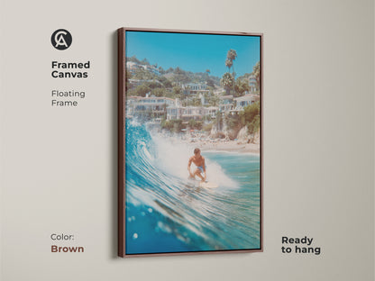 A framed canvas art print featuring a surfer riding a wave. The floating brown frame enhances the artwork. This piece is ready to hang and brings a touch of the ocean into your home. The artwork has a warm and natural aesthetic.