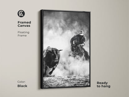 Framed canvas art displays a cowboy riding a bull. The Western action scene print is monochrome cowboy decor. This grayscale bull art is perfect for a man cave. Ready to hang with a floating frame in black.