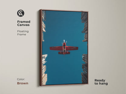 Framed aviation photography print on canvas with a brown floating frame. A crimson red aeroplane soars above urban skyscrapers against a deep blue sky. Ready to hang. This artwork makes a unique pilot gift. A great piece for any wall.