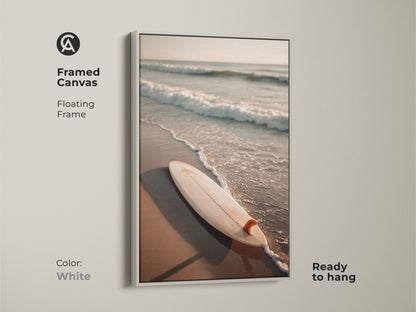 White framed canvas art featuring a surfboard on the beach. The clean white frame offers a fresh modern look. Ready to hang this artwork brightens any room. Ideal for minimalist or coastal-themed interiors. Bring the beach into your home with this crisp white framed art.