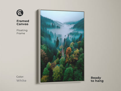 Framed canvas art featuring a misty forest valley. The white floating frame provides a clean modern look. This artwork is ready to hang. It will brighten any room. The lush trees and peaceful fog create a tranquil ambiance.