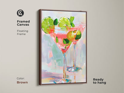 Framed Canvas art. The floating frame is brown. It displays two cocktail glasses filled with a pink beverage. Limes and mint garnish the drinks. This ready-to-hang artwork adds a modern touch to your space.