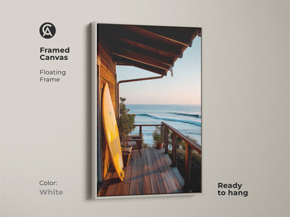 A framed canvas art piece featuring a surfboard on a porch with an ocean view. This floating frame in white enhances the coastal artwork. The ready-to-hang surf art brings a beach vibe to any space. Perfect for ocean-themed home decor. Enjoy this framed art print.