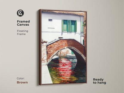 Framed canvas showcases a traditional Venetian canal scene with a red brick bridge. The brown floating frame highlights the European cityscape art. Ready to hang and perfect for adding charm to your home.