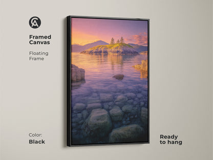 Framed Canvas Island Seascape with a black floating frame. The Coastal Sunset Wall Art features ocean landscape photography of a rocky shoreline. Clear water reveals stones. The purple orange sky artwork is ready to hang.