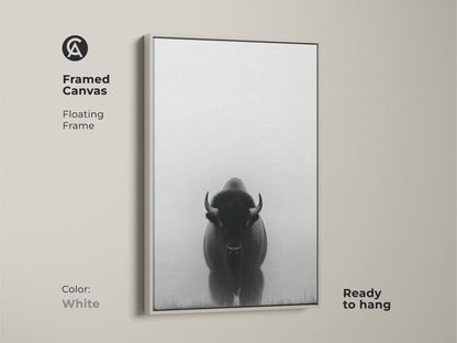 A white frame surrounds a canvas with minimalist bison art. This black and white prairie canvas is ready to hang. The wildlife animal landscape print makes for a rustic farmhouse touch.