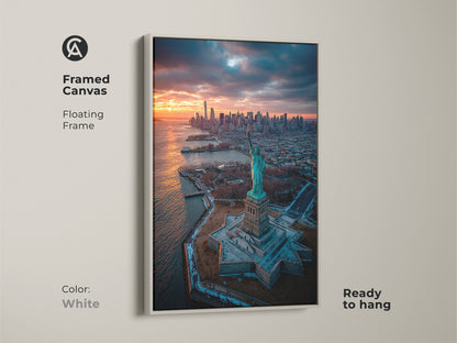 This framed canvas displays the Statue of Liberty with a sunset backdrop. The white floating frame creates a clean modern look. This artwork is ready to hang offering easy styling. It is perfect for minimalist spaces.
