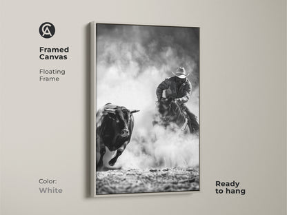 Framed canvas art displays a cowboy riding a bull. The Western action scene print is monochrome cowboy decor. This grayscale bull art is perfect for a man cave. Ready to hang with a floating frame in white.
