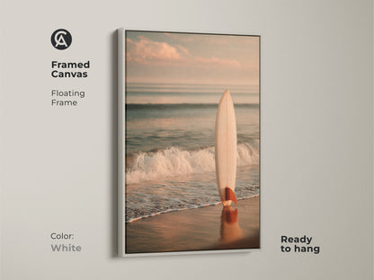 White framed canvas art featuring a surfboard on the beach. The floating frame enhances the artwork. It is ready to hang. This piece brings a touch of coastal charm to your home. Perfect for ocean lovers.