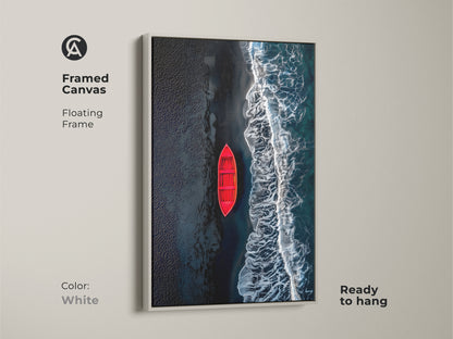 Framed canvas art featuring a red boat on a beach with black sand. The artwork has a clean white floating frame. This canvas is ready to hang and will elevate any room's decor. A perfect addition to your art collection.