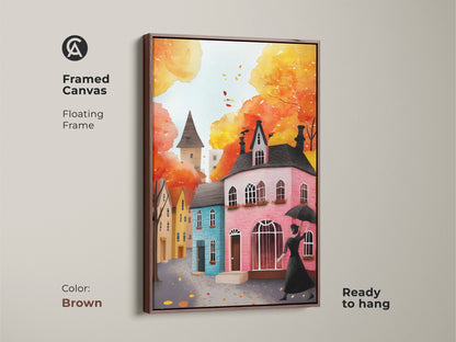 Framed canvas art print of a watercolor autumn cityscape with a brown floating frame. This artwork features a woman with an umbrella and charming houses. Ready to hang and perfect for fall decor. The warm yellow orange and red tones create a cozy eclectic feel. Add a touch of autumn charm to your residential decor.