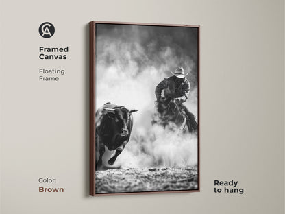 Framed canvas art shows a cowboy riding a bull. The Western action scene print is monochrome cowboy decor. This grayscale bull art is perfect for a man cave. Ready to hang with a floating frame in brown.