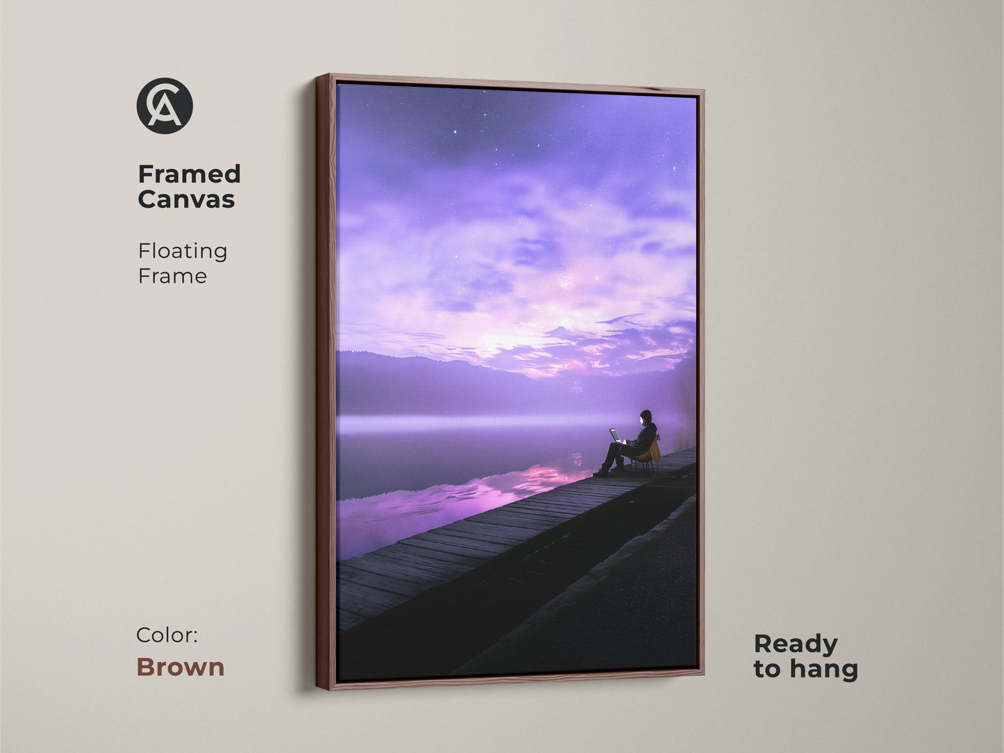 Framed canvas art showing a person working on a laptop by a tranquil lake. The floating frame is in brown. This modern landscape artwork features a violet skyscape. Ready to hang. Perfect wall decor for adding a calming touch to your workspace.