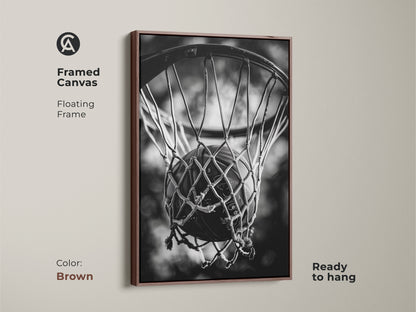 Brown framed basketball canvas art. This floating frame canvas is ready to hang. The brown frame enhances the black and white artwork of a basketball in a net. Ideal for sports enthusiasts and home decoration.