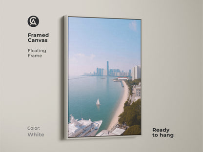 A framed canvas showing coastal cityscape art with a yacht and sailboat. This floating frame artwork is ready to hang and features a white frame. The ocean view art print features modern aqua blue artwork. It is a contemporary cityscape print perfect for travel lovers. The coastal scene offers nautical themed wall decor.