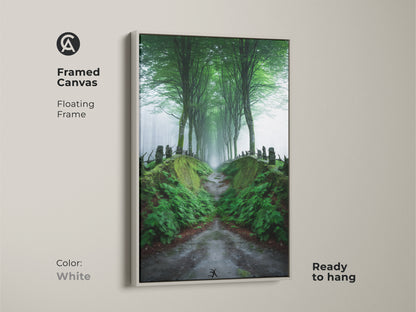 Framed canvas artwork of a misty forest path with a white floating frame. The lush greenery and tree-lined road create a Scandinavian woodland scene. Ready to hang this nature landscape painting brings a refreshing touch to your home. Perfect for any room.