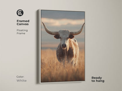 Framed canvas featuring a longhorn cattle in a rustic Tuscan setting. The white floating frame highlights this farmhouse animal artwork. This piece is perfect for beige neutral wall art and easy to hang.
