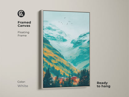 A framed canvas print displays a teal mountain valley artwork. Orange and white mountains tower over a village nestled in evergreens. Birds fly in the misty sky. This framed art is a clean white color.